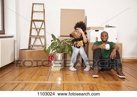 Picture - A laughing couple taking a coffee break while moving house. Fotosearch