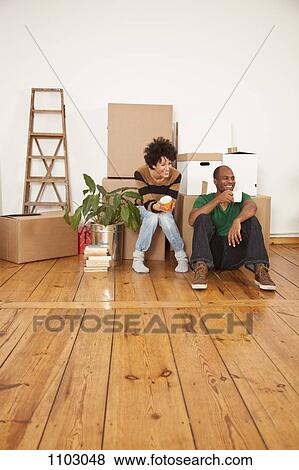 Stock Photo - A laughing couple taking a coffee break while moving house. Fotosearch