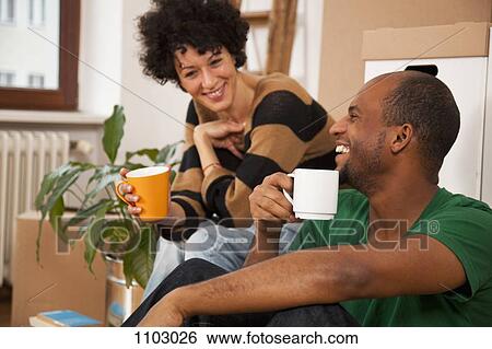 A laughing couple taking a coffee break while moving house, close-up View Large Photo Image Stock Photograph - A laughing couple taking a coffee break while moving house, close-up. Fotosearch