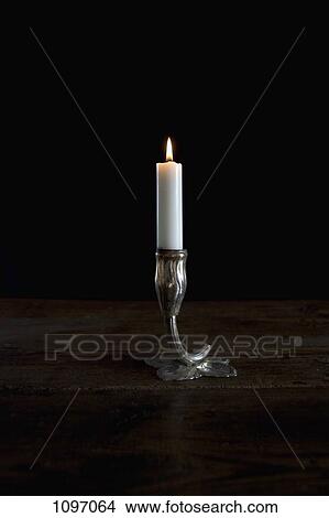 A lit candle in a silver candlestick holder View Large Photo Image Picture - A lit candle in a silver candlestick holder. Fotosearch