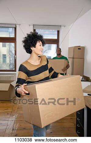 Stock Photo - A man and woman carrying moving boxes, focus on woman. Fotosearch