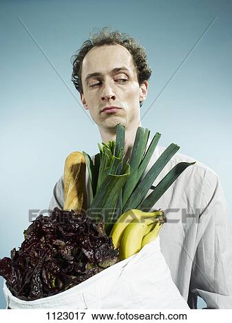 A man carrying a shopping bag of groceries and looking suspiciously to the side View Large Photo Image Stock Photo - A man carrying a shopping bag of groceries and looking suspiciously to the side. Fotosearch