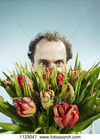 A man nervously hiding behind a bouquet of tulips View Large Photo Image Stock Photo - A man nervously hiding behind a bouquet of tulips. Fotosearch
