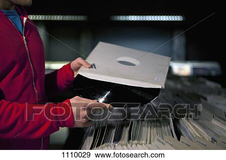A man taking a record out of its sleeve in a record store View Large Photo Image Stock Photo - A man taking a record out of its sleeve in a record store. Fotosearch