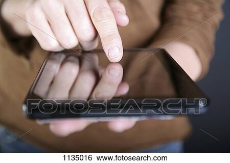 Stock Photograph - A man using a digital tablet, close-up of hand. Fotosearch