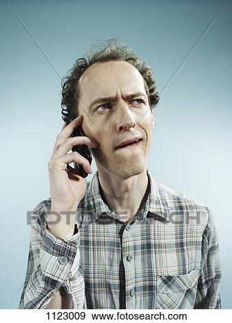 A man using a mobile phone with a confused look on his face View Large Photo Image Stock Photo - A man using a mobile phone with a confused look on his face. Fotosearch