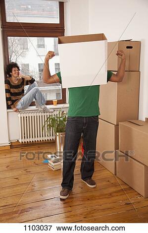 A man with a box on his head flexing his muscles while woman watches View Large Photo Image Stock Photo - A man with a box on his head flexing his muscles while woman watches. Fotosearch