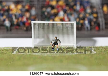 Stock Photo - A miniature soccer goalie figurine guarding the goal post. Fotosearch