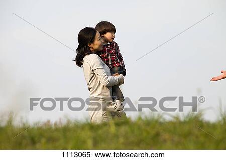 Stock Photography - A mother carrying her son outdoors. Fotosearch