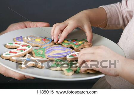 A mother sharing a plate of Christmas cookies with her daughter, focus on hands View Large Photo Image Stock Photography - A mother sharing a plate of Christmas cookies with her daughter, focus on hands. Fotosearch