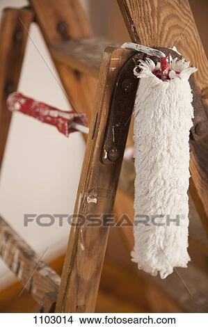 Picture - A paint roller hanging from a wood step ladder, close-up. Fotosearch