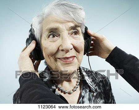 A person putting headphones on a senior woman View Large Photo Image Picture - A person putting headphones on a senior woman. Fotosearch