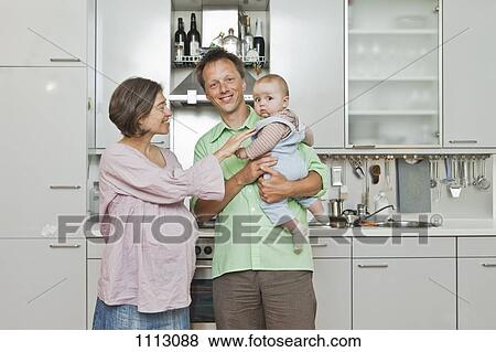 Stock Photo - A pregnant woman and her partner posing with their toddler daughter. Fotosearch