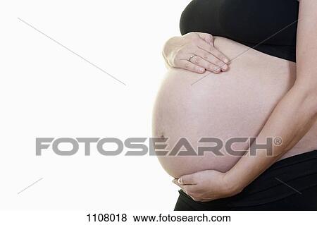 A pregnant woman holding her belly, midsection, side view View Large Photo Image Stock Photo - A pregnant woman holding her belly, midsection, side view. Fotosearch