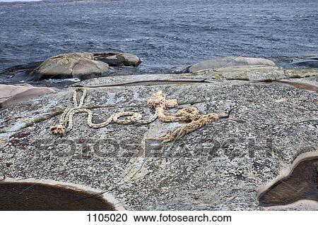 Stock Image - A rope spelling HATE on a rocky coastline. Fotosearch