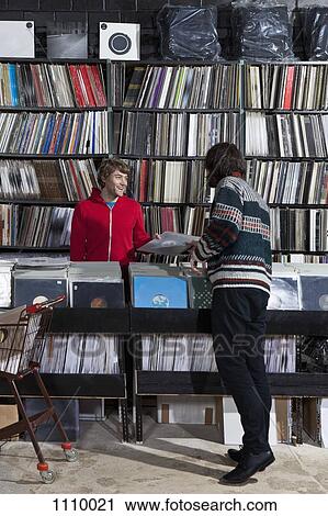 A sales clerk giving a record to a customer in a record store View Large Photo Image Stock Image - A sales clerk giving a record to a customer in a record store. Fotosearch