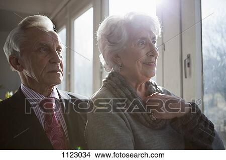 Picture - A senior couple looking out a window at the view. Fotosearch