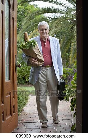 A senior man arriving home with a bag of groceries and a briefcase View Large Photo Image Stock Photo - A senior man arriving home with a bag of groceries and a briefcase. Fotosearch