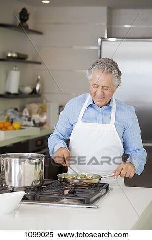 A senior man cooking vegetables in a saute pan View Large Photo Image Stock Photography - A senior man cooking vegetables in a saute pan. Fotosearch