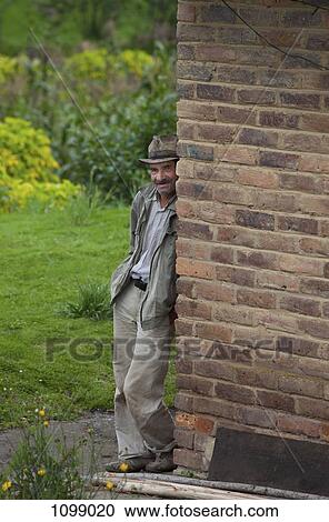 A senior man leaning against a wall View Large Photo Image Stock Image - A senior man leaning against a wall. Fotosearch
