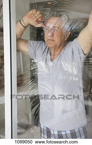 A senior man looking out a window View Large Photo Image Stock Image - A senior man looking out a window. Fotosearch