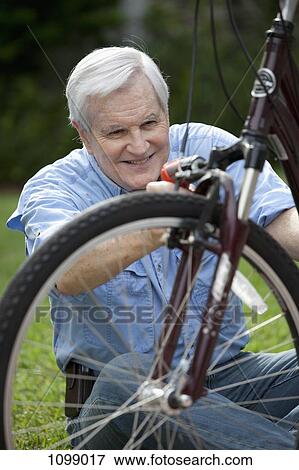A senior man repairing a bicycle View Large Photo Image Stock Photo - A senior man repairing a bicycle. Fotosearch