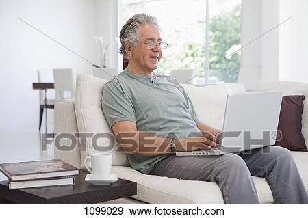 Stock Photo - A senior man using a laptop at home. Fotosearch