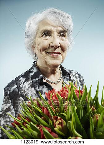 A senior woman receiving a bouquet of tulips View Large Photo Image Stock Photo - A senior woman receiving a bouquet of tulips. Fotosearch