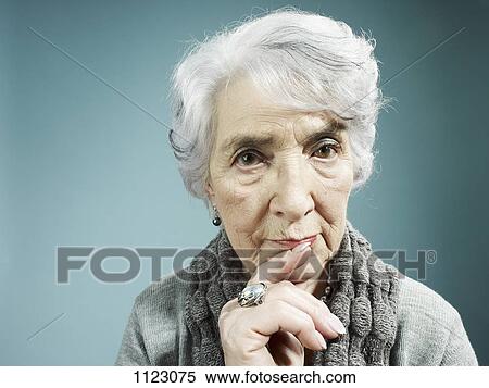 Stock Photography - A senior woman thinking with her index finger to her lips. Fotosearch