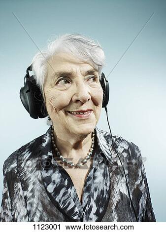 Stock Image - A senior woman wearing headphones. Fotosearch