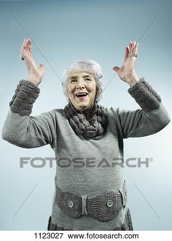 Stock Photo - A senior woman with her arms raised in celebration. Fotosearch