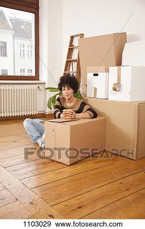 Stock Photo - A serious woman taking a coffee break while moving house. Fotosearch