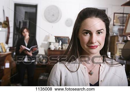 A smiling woman standing in an antiques shop View Large Photo Image Stock Photo - A smiling woman standing in an antiques shop. Fotosearch