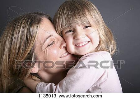 Stock Image - A smiling young girl hugging her mother, close-up. Fotosearch