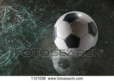 Stock Photo - A soccer ball on broken glass. Fotosearch