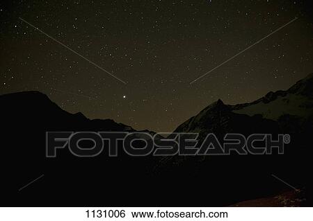 Stock Photograph - A starry sky behind silhouetted mountains. Fotosearch