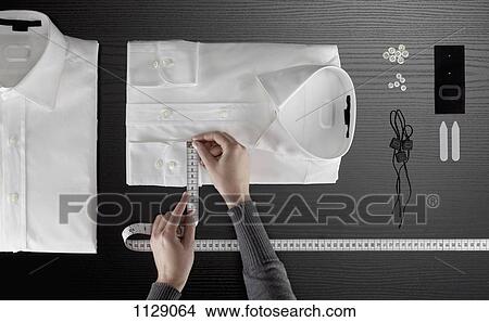 A tailor measuring a button down shirt, focus on hands View Large Photo Image Picture - A tailor measuring a button down shirt, focus on hands. Fotosearch