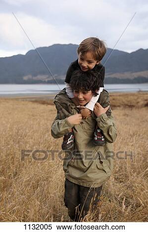 A teenage boy carrying his younger brother on his shoulders View Large Photo Image Stock Photography - A teenage boy carrying his younger brother on his shoulders. Fotosearch