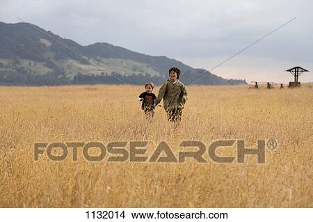 A teenage boy running with his younger brother in a field View Large Photo Image Picture - A teenage boy running with his younger brother in a field. Fotosearch