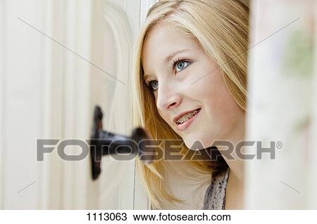 Stock Image - A teenage girl looking out a window day dreaming. Fotosearch