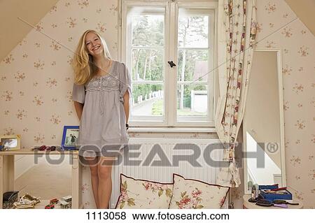 A teenage girl standing in her bedroom smiling View Large Photo Image Stock Photo - A teenage girl standing in her bedroom smiling. Fotosearch