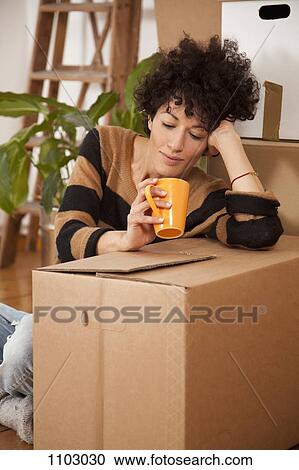 A tired woman taking a coffee break while moving house View Large Photo Image Stock Image - A tired woman taking a coffee break while moving house. Fotosearch