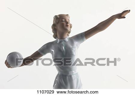 Stock Photo - A vintage porcelain statue of a woman preparing to throw a ball. Fotosearch
