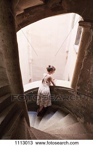 A woman leaning on a staircase railing and looking outside View Large Photo Image Stock Image - A woman leaning on a staircase railing and looking outside. Fotosearch
