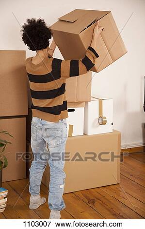 Stock Photo - A woman lifting a moving box and placing on a stack of boxes. Fotosearch