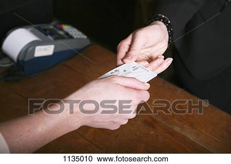 Stock Image - A woman paying with a credit card in a shop, close-up of hands. Fotosearch