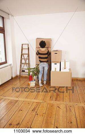 A woman pushing a moving box into place on top of a stack of boxes View Large Photo Image Picture - A woman pushing a moving box into place on top of a stack of boxes. Fotosearch