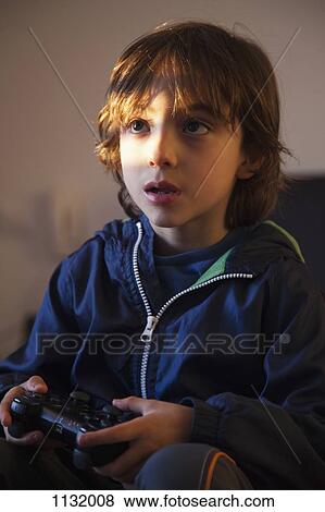 A young boy holding a video game controller looking concentrated View Large Photo Image Stock Photo - A young boy holding a video game controller looking concentrated. Fotosearch