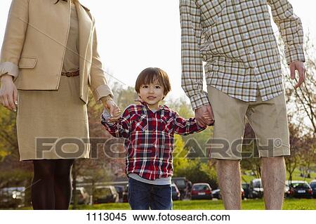 Stock Photography - A young boy in between his parents, holding hands. Fotosearch