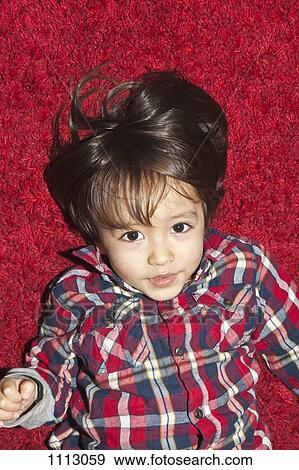 A young boy lying on a red carpet View Large Photo Image Stock Photo - A young boy lying on a red carpet. Fotosearch